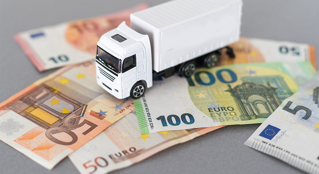 modellino di camion appoggiato sopra ad alcune banconote